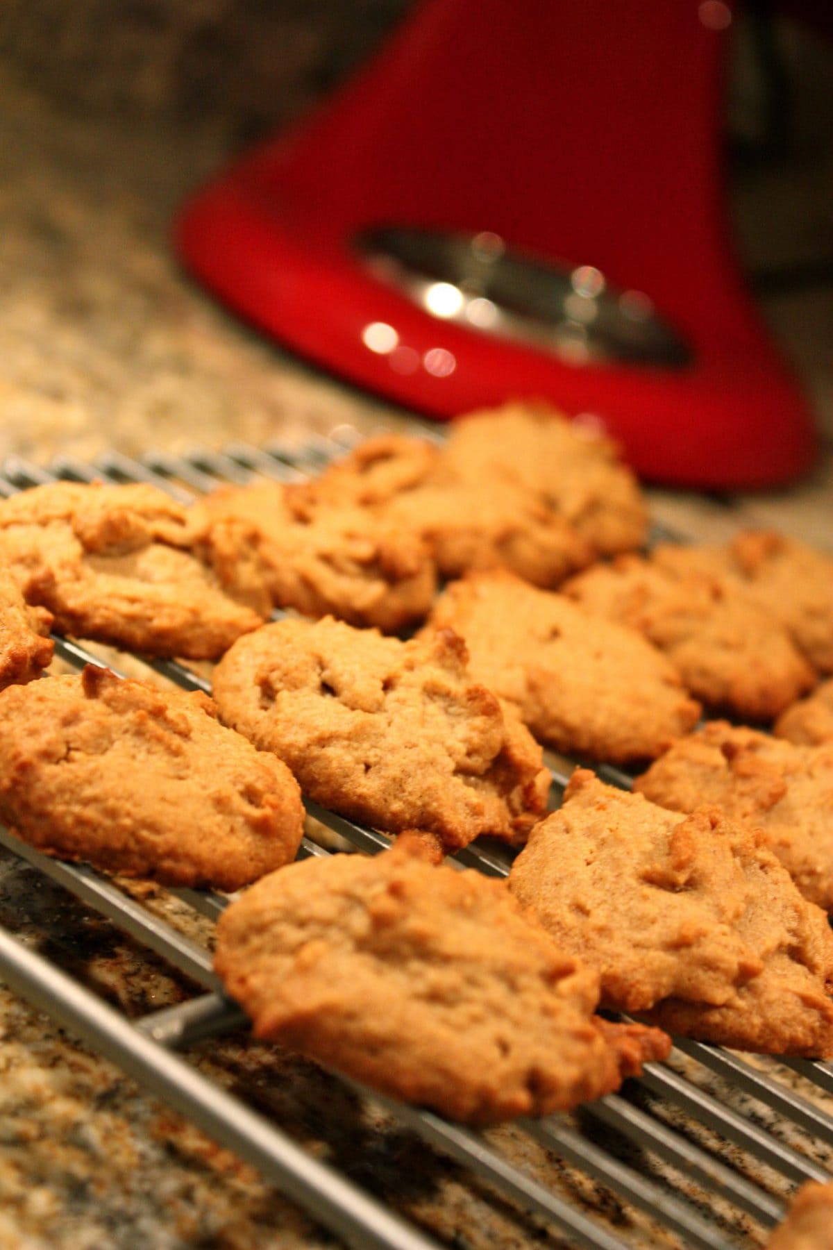 gluten free peanut butter cookies on a cookie sheet with a red kitchen aid mixer in the background