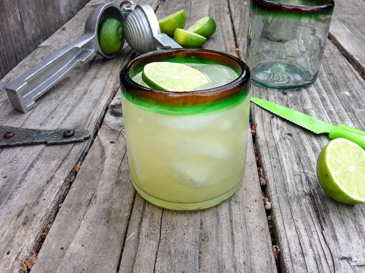 paleo margaritas in a cup along with a fresh lime next to it