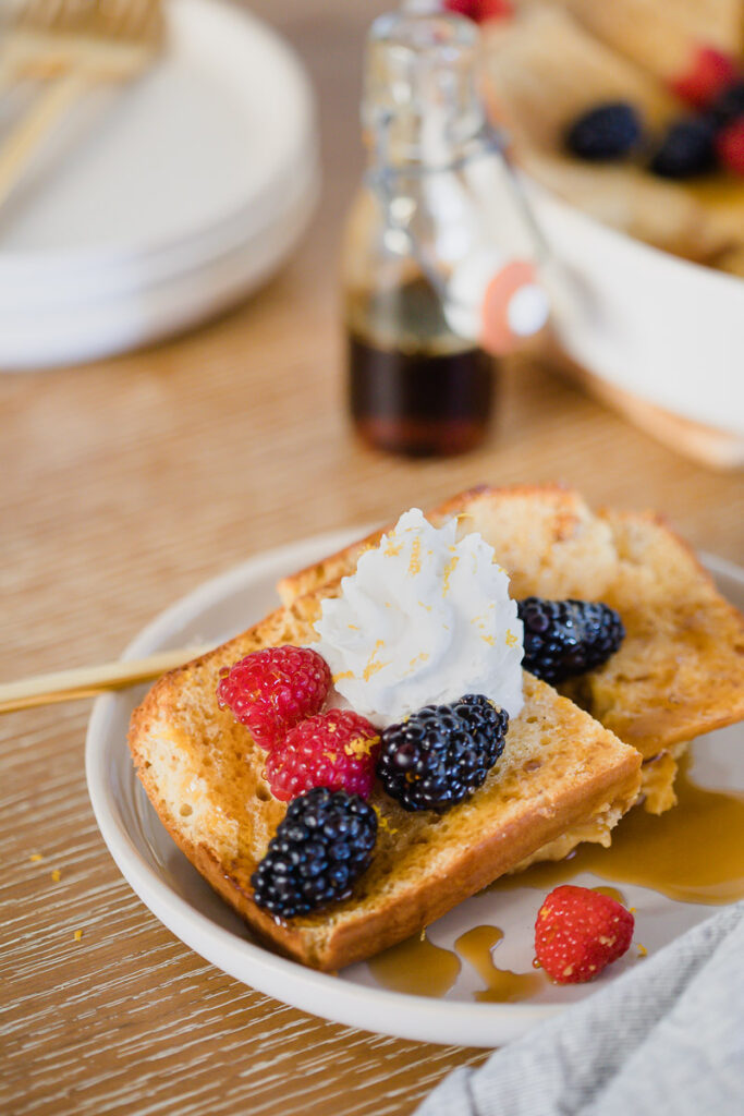 Meyer Lemon French Toast served on a white plate topped with whipped cream and fresh berries