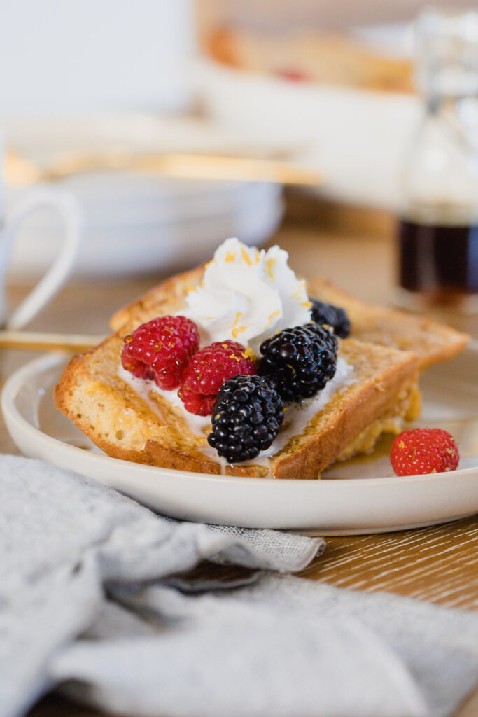 Meyer Lemon French Toast served on a white plate topped with whipped cream and fresh berries