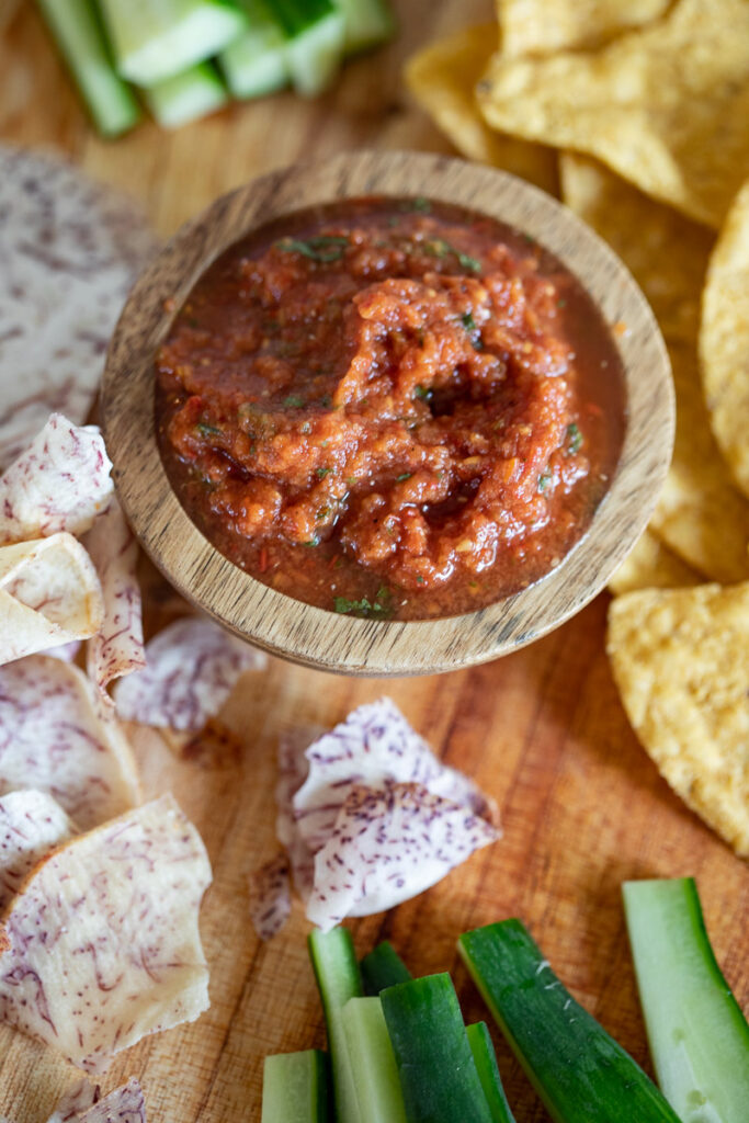 paleo restaurant style salsa in wooden bowl on cutting board served with chips and veggies for dipping