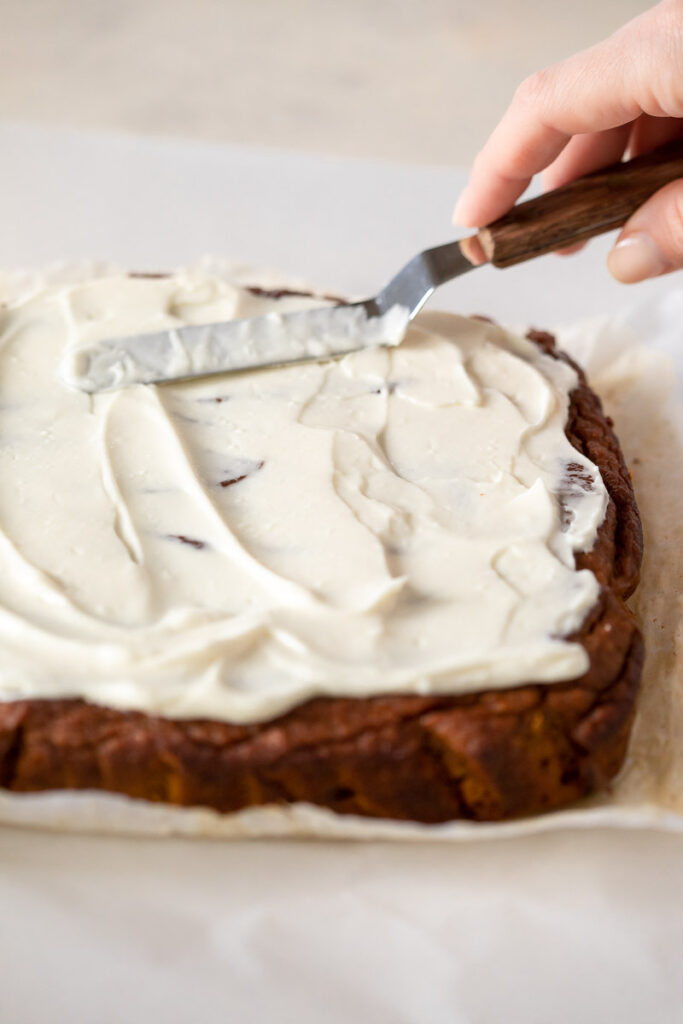 cream cheese icing being spread on nut-free pumpkin spice cake