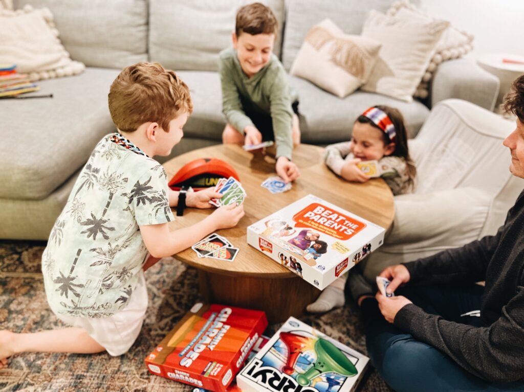 two young boys and one young girl sit around a table playing multiple board games for a kid-friendly game night