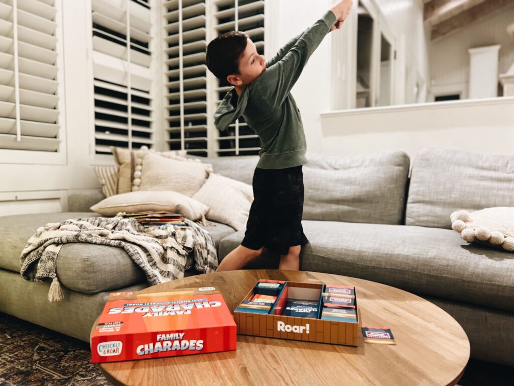 Young boy plays the game charades in a living room for a kid-friendly game night 