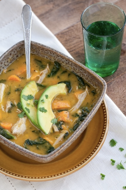 Danielle Walker's Mexican Instant Pot Soup served in a brown square bowl with a glass of water on the side. Bowl is placed on white linen. 