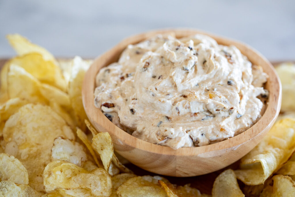 dairy-free creamy onion dip served in a wooden bowl, surrounded by potato chips