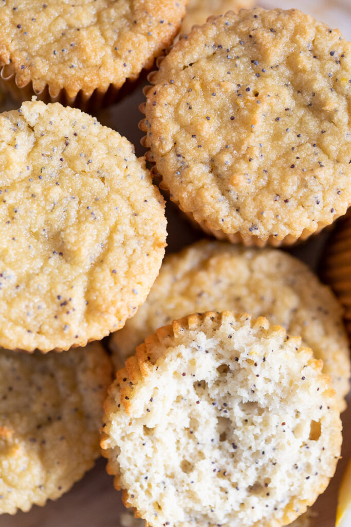 A close up view from the top of a stack of Gluten-Free Lemon Poppy Seed Muffins on an etched wooden platter