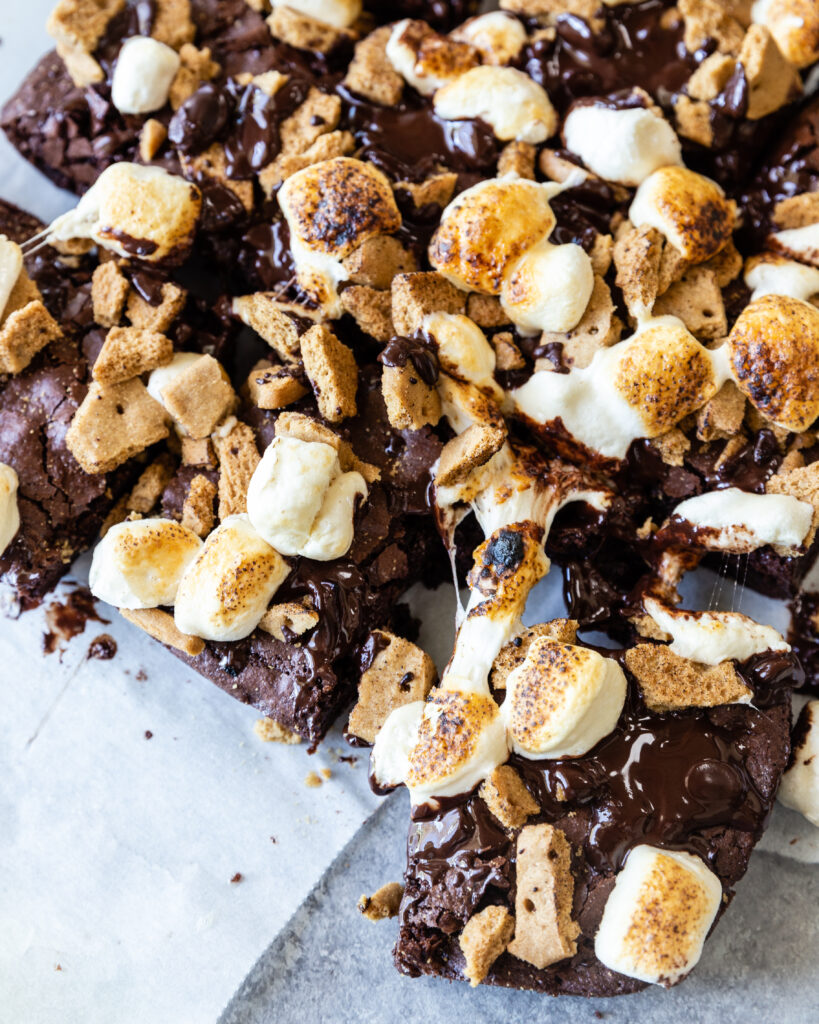 A decadent gluten-free s'mores brownie cut into squares, laying on parchment paper