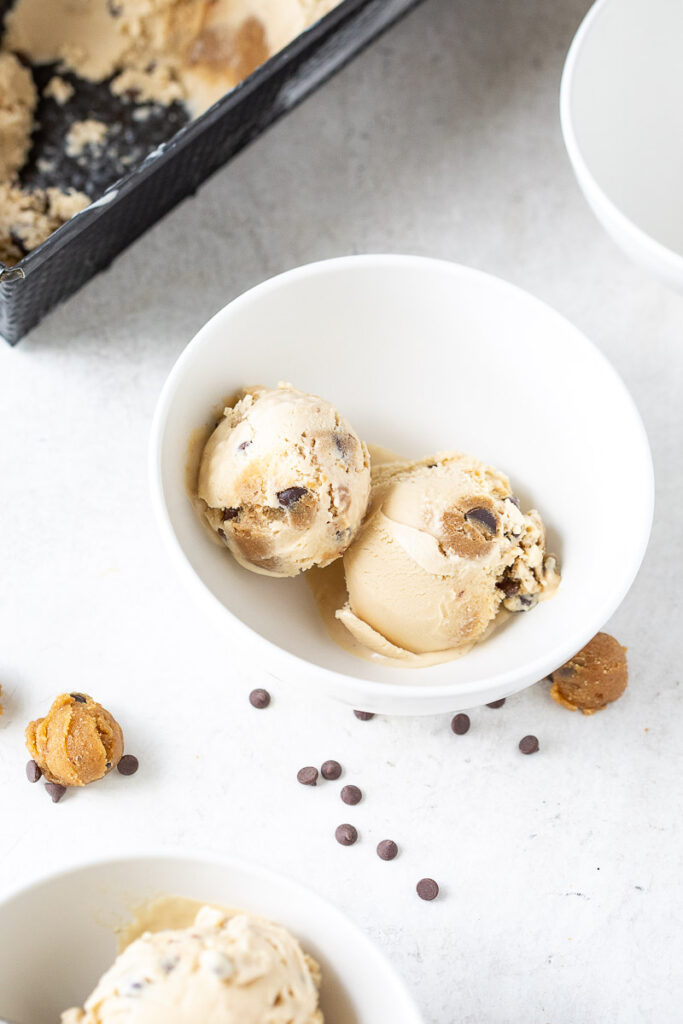 Scoops of Dairy-Free Chocolate Chip Cookie Dough Ice Cream in white bowls on a marble counter