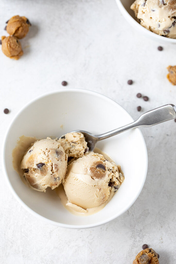 two scoops of Dairy-Free Chocolate Chip Cookie Dough Ice Cream in a white bowl with a spoon 