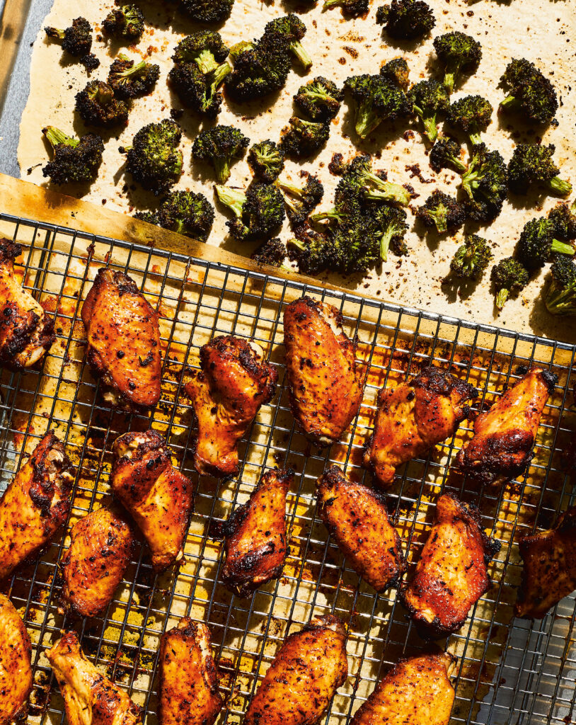 Cooked Paleo Jerk Chicken and burnt broccoli on sheet pans lined with parchment paper 