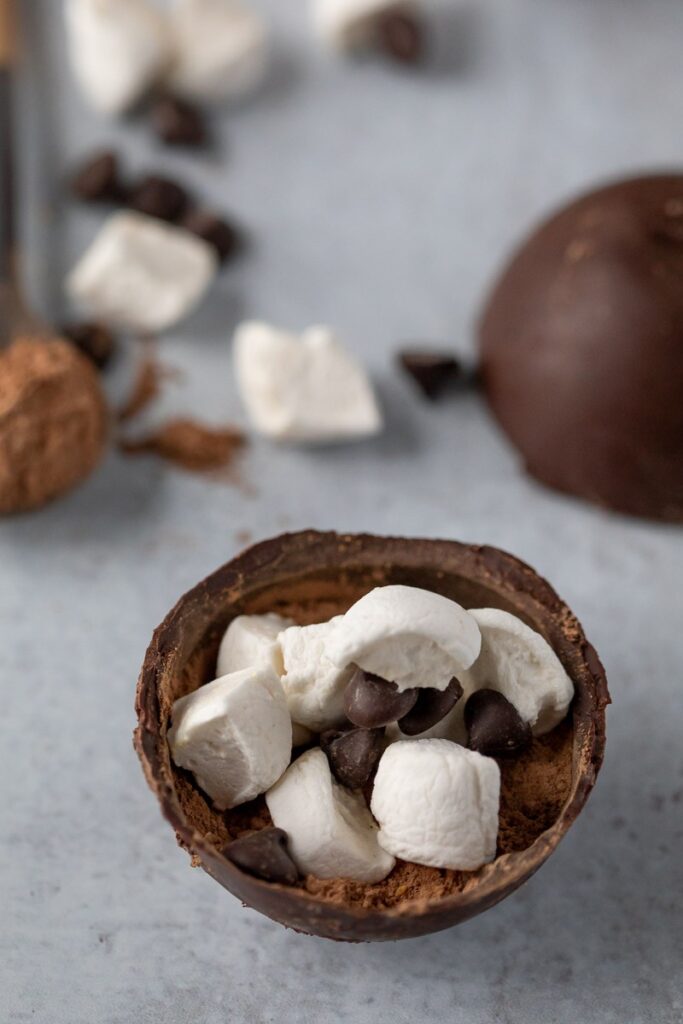 dairy free hot chocolate bomb cut in half, showing interior stuffed wth marshmallows, chocolate chips and dairy free hot cocoa mix