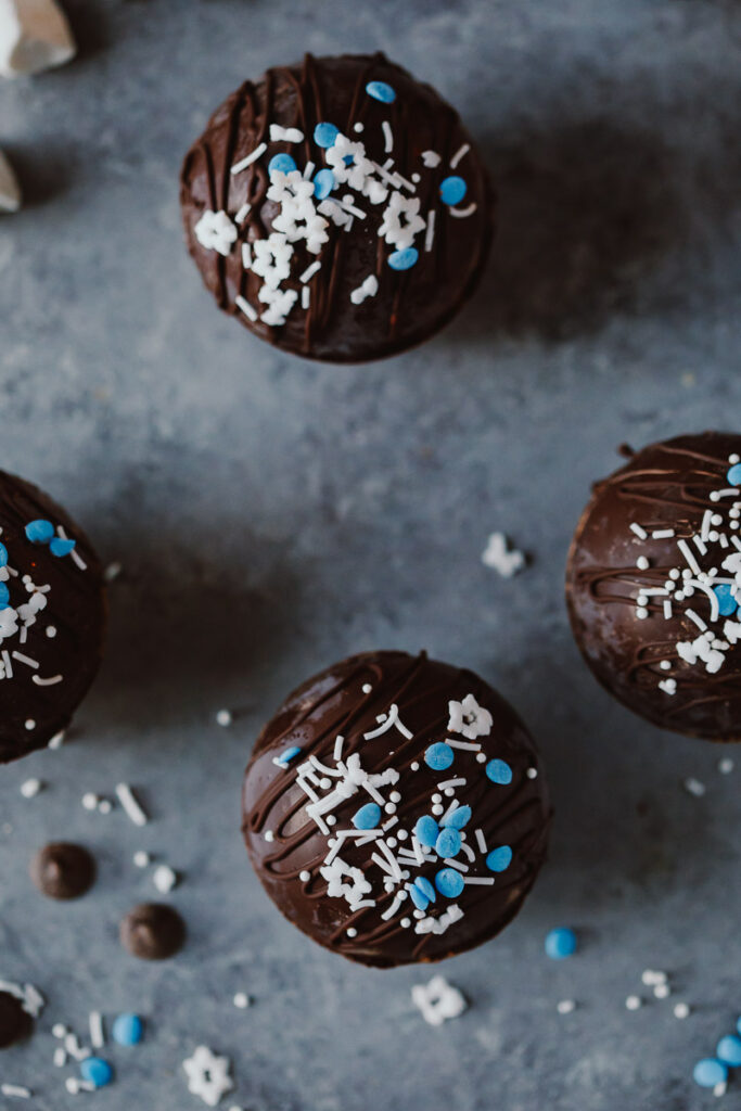 Dairy-Free Hot Cocoa Bombs pictured with white and blue sprinkles on a gray countertop