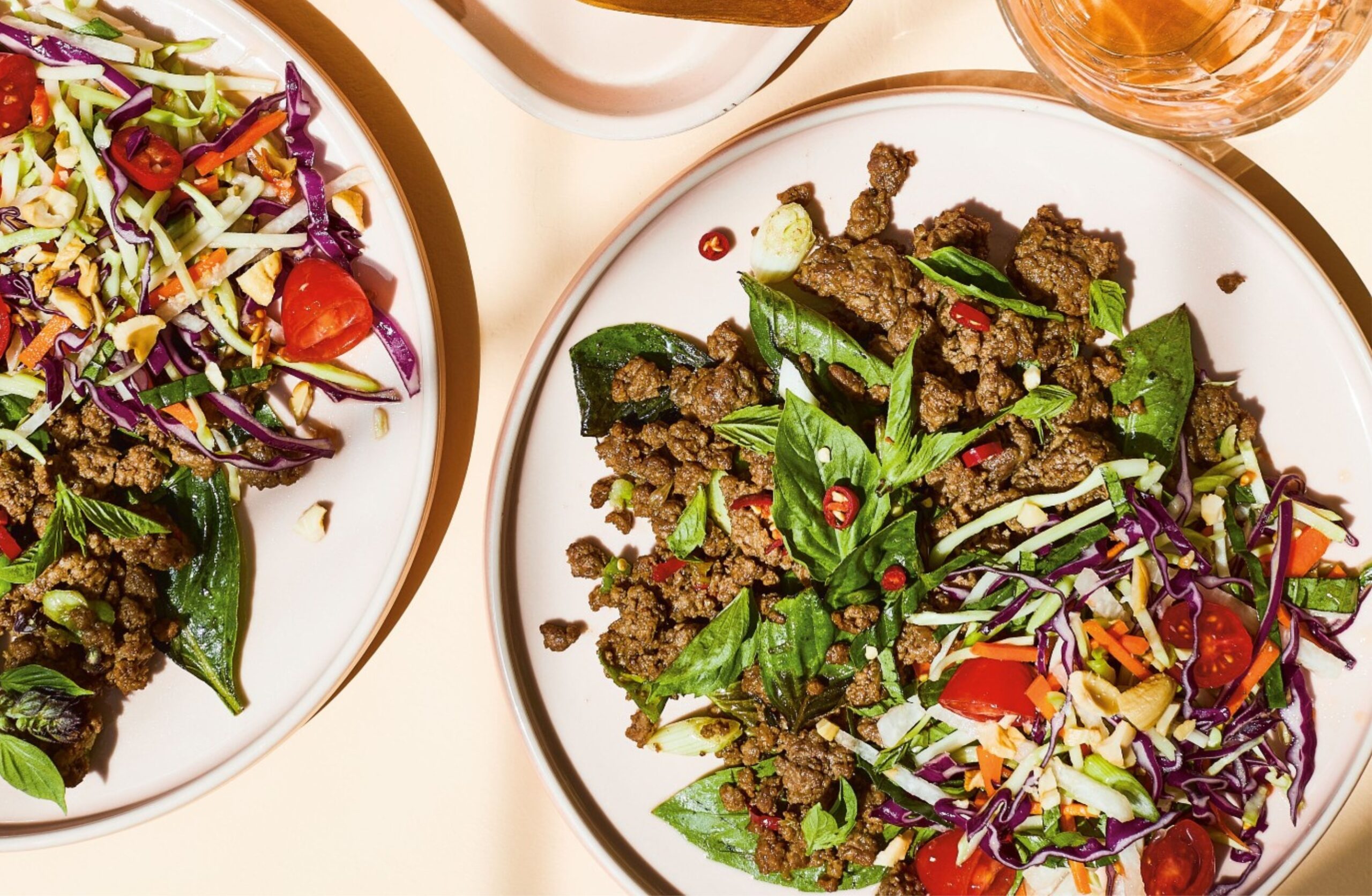 image of two plates of thai basil beef with sweet and sour salad.