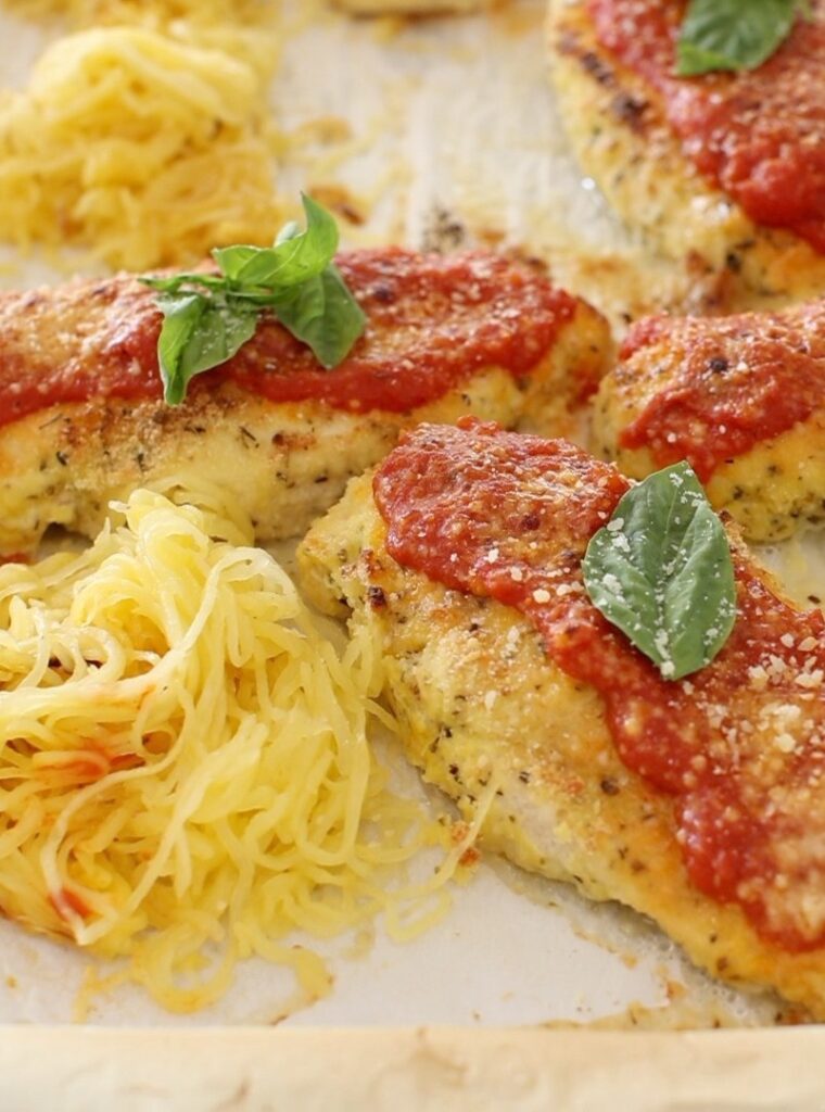 chicken parmesan alongside spaghetti squash on a sheet pan