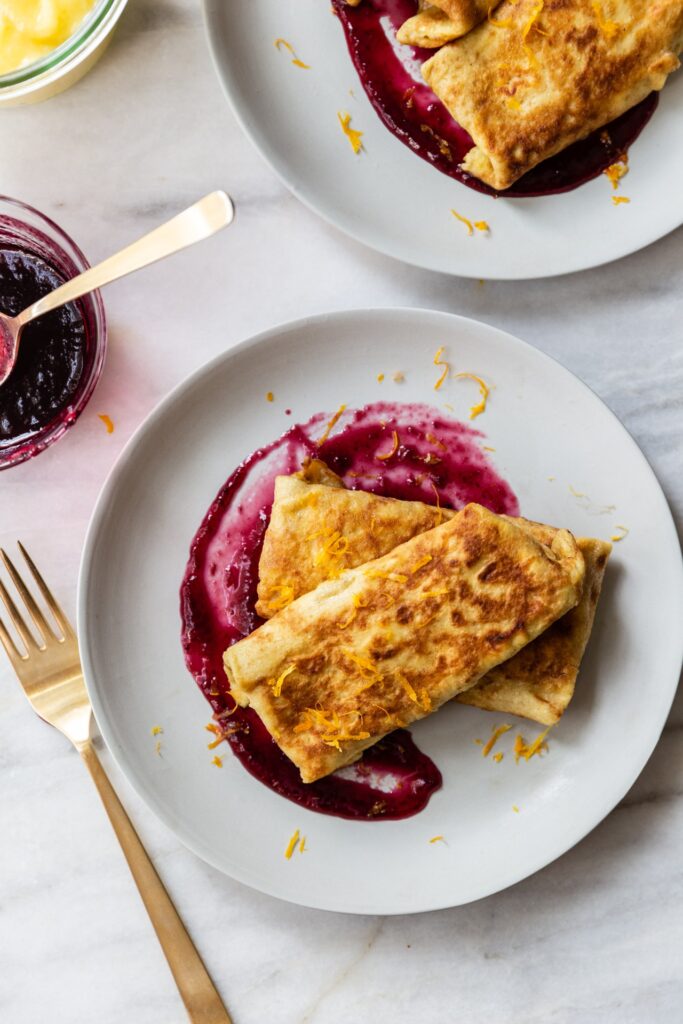 image of dairy free cheese blintz with lemon curd and blueberry on a table with a fork