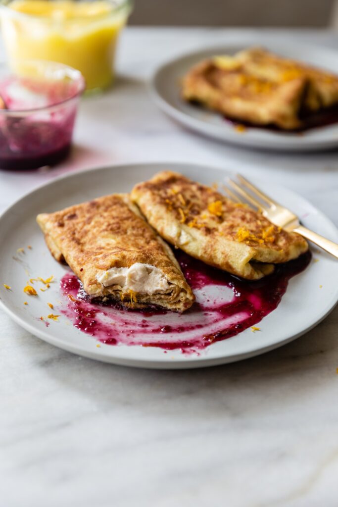 image of a dairy free cheese blintz with lemon curd and blueberry on a plate cut in half