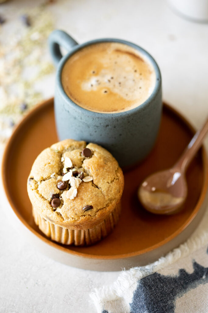 image of banana protein muffin on a plate with a cup of coffee