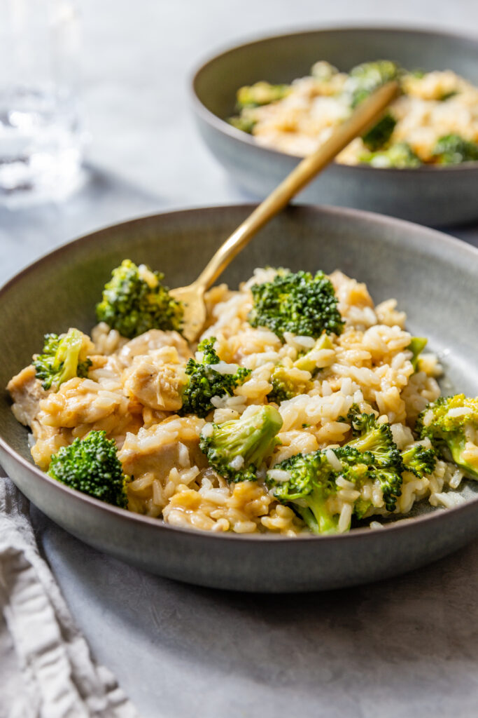 image of instant pot dairy free chicken broccoli rice casserole in two bowls with spoons on a counter from a side view.