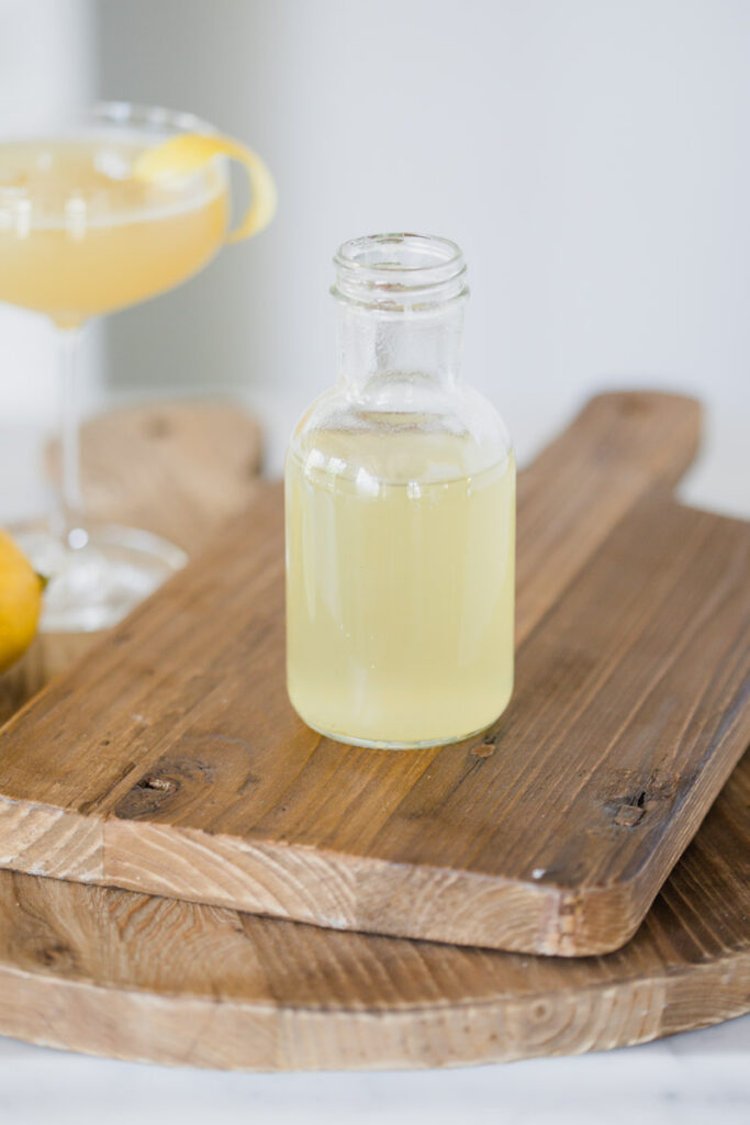 image of a bottle of honey simple syrup on a wood cutting board