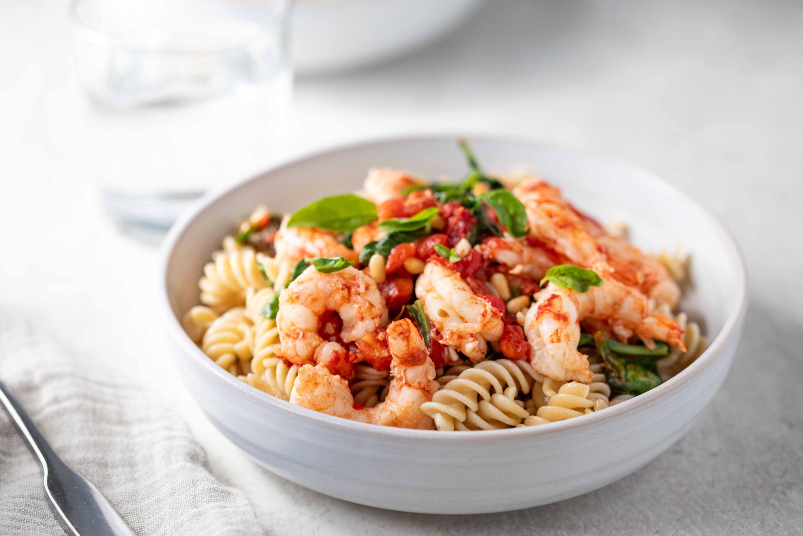 image of heirloom tomato pasta with roasted shrimp in a bowl on a counter