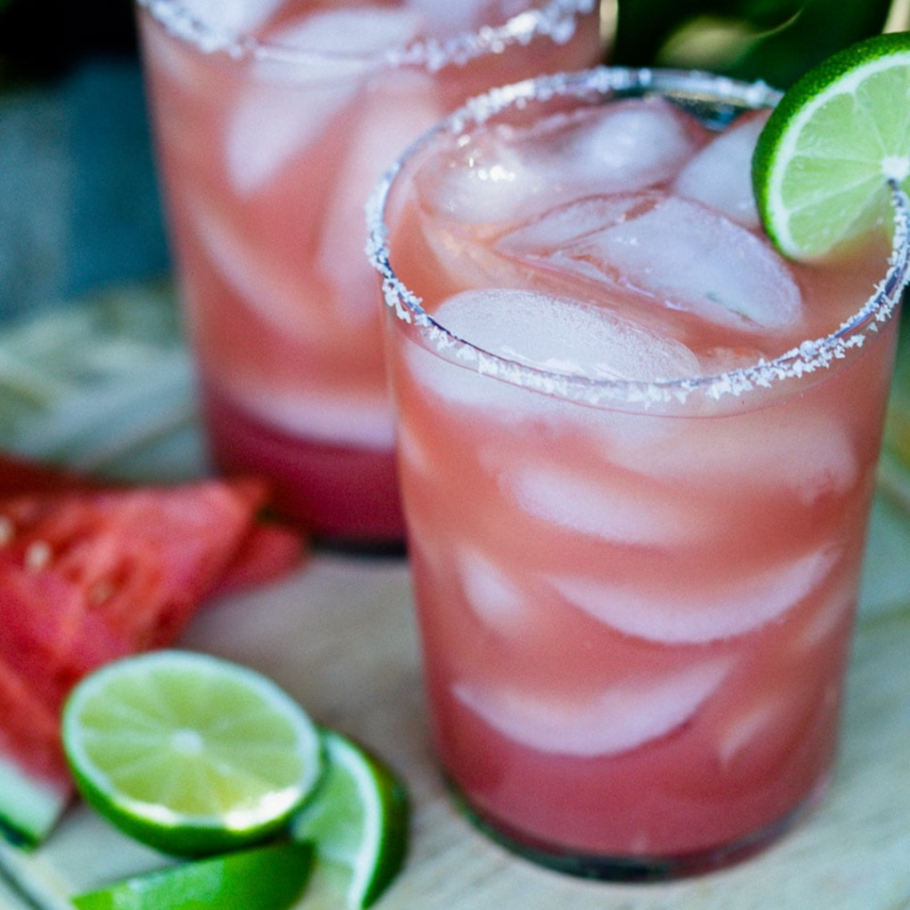 image of two glasses of watermelon margaritas with sliced limes